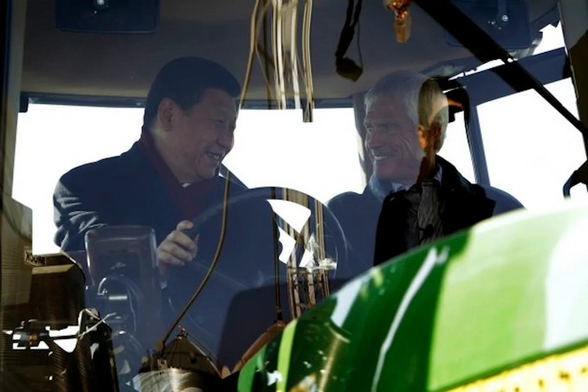 In 2012 in Maxwell, Iowa, population 807, Xi Jinping visits the farm of Rick Kimberley and is behind the wheel of the tractor with him. Xi and Kimberely look into each other's face and both are smiling. 
