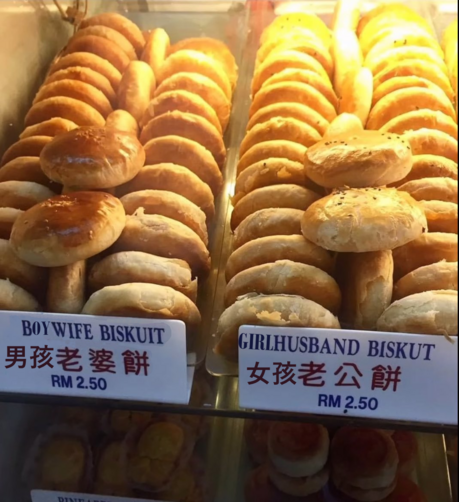 in the warm glow of a Chinese bakery's display shelves, a hastily photoshopped set of shelves reading in English and Chinese "Boywife Biskuit" and a "Girlhusband biskut" next to each other. Both of them look like very similar golden brown flaky pastries and cost only RM 2.50.
