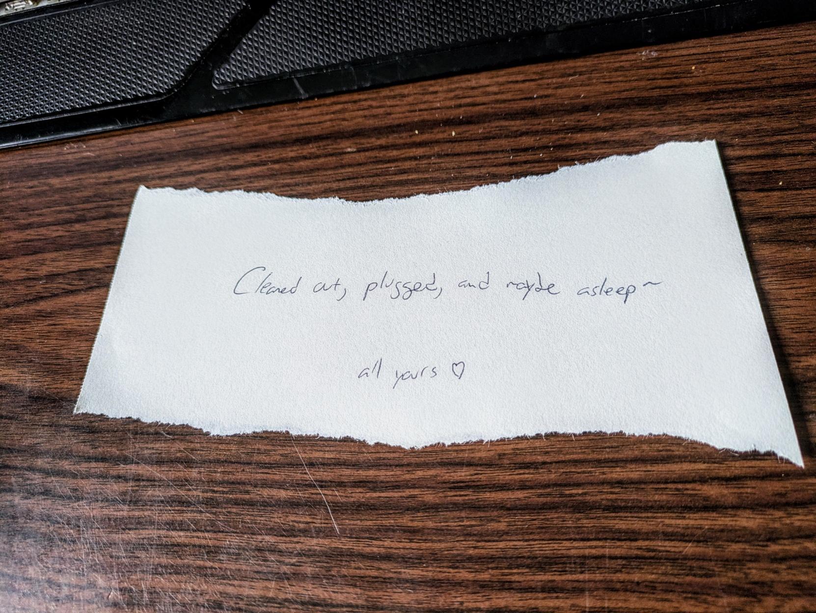 A photo of a note found under my keyboard: "Cleaned out, plugged, and maybe asleep — all yours ❤️"